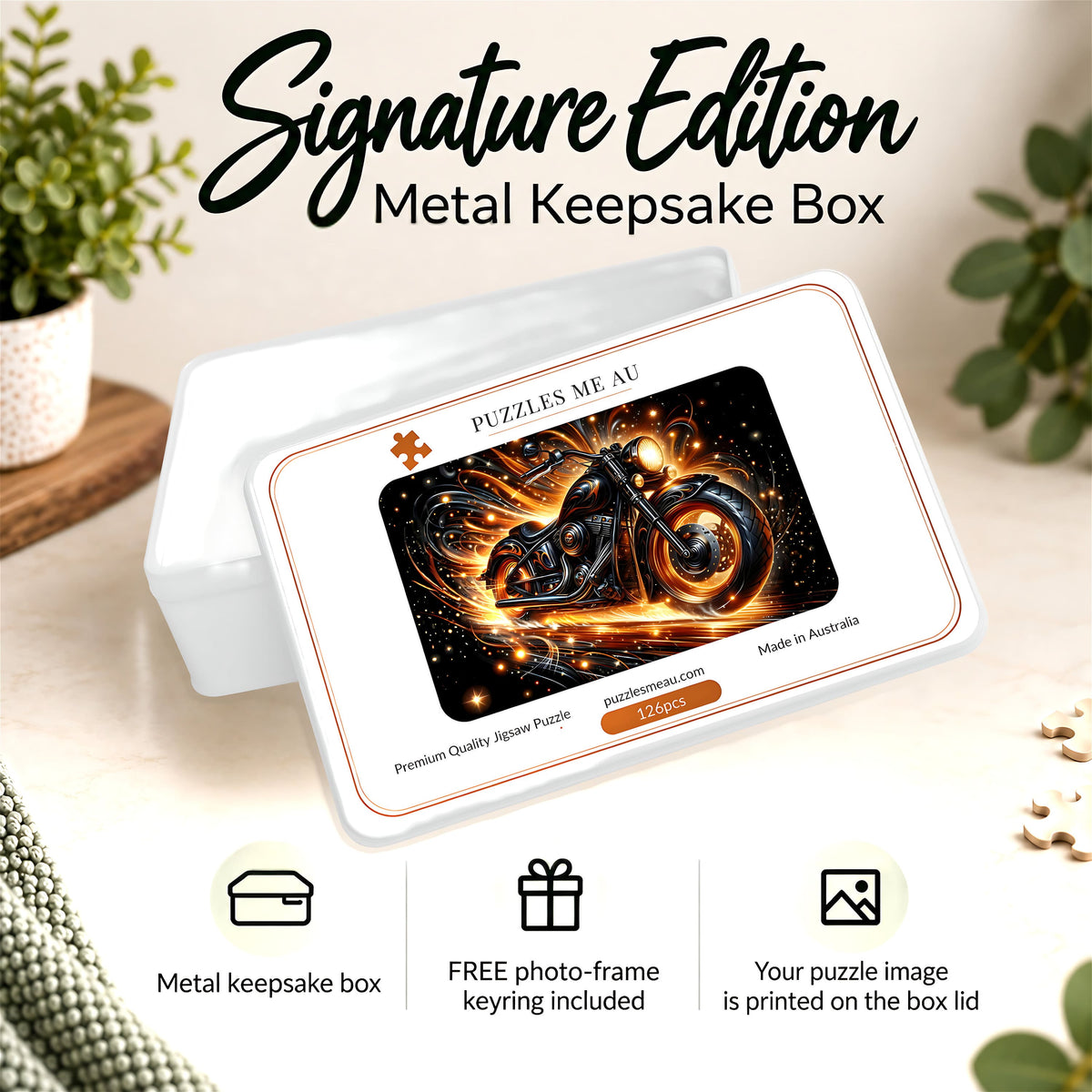 A white metal keepsake box shown at an angle with its lid leaning on top. The lid features a printed puzzle card design with a motorcycle illustration in black, orange, and gold tones, plus the text 'PUZZLES ME AU' and 'Made in Australia.
