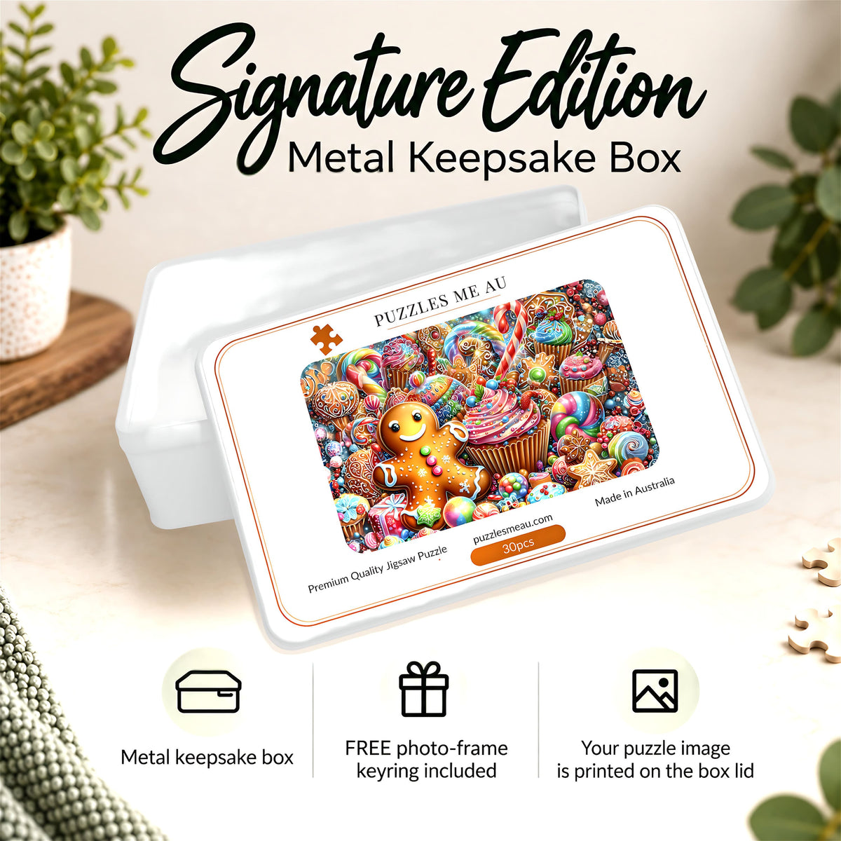 A white rectangular metal keepsake box with rounded corners sits on a light beige surface. The lid is angled forward and displays a colorful printed puzzle cover featuring a gingerbread man and cupcakes, with the text 'PUZZLES ME AU' and 'Made in Australia.